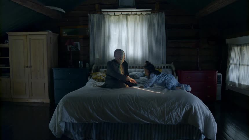 A woman and child in a bed looking at something