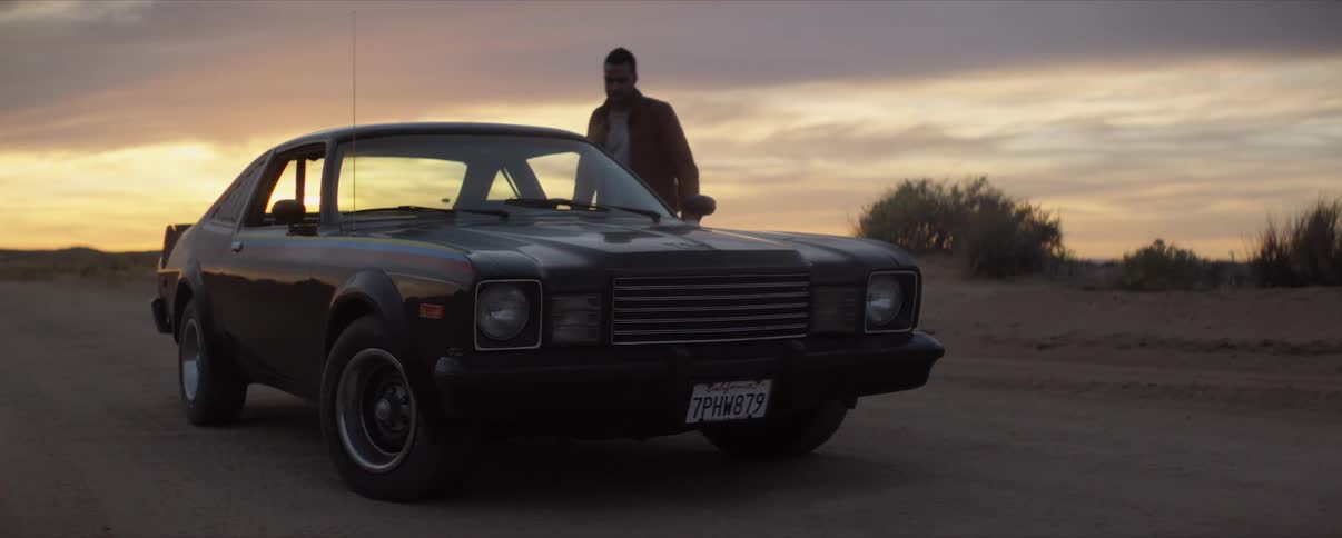man entering Classic Muscle Car In Desert at sunrise