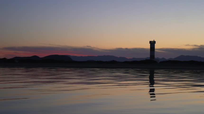 The sunsets behind the mountains in front of the water