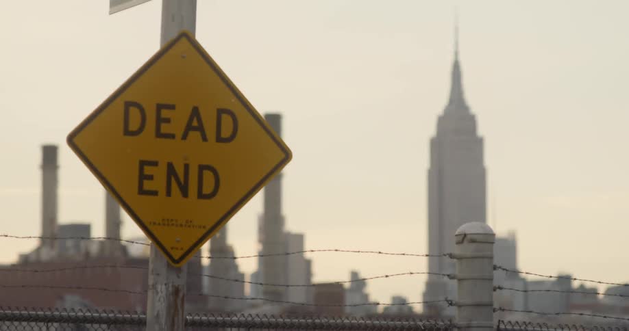 Dead end sign outside of a city skyline