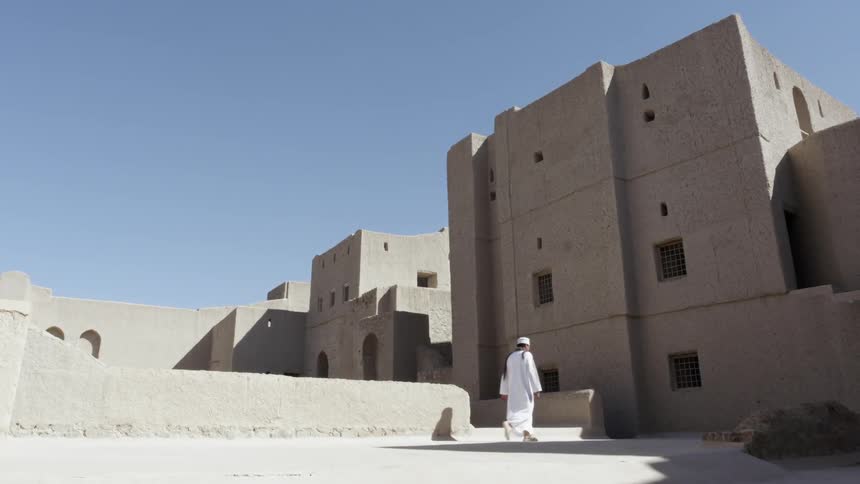 A man in a white religious garb walks into the shade