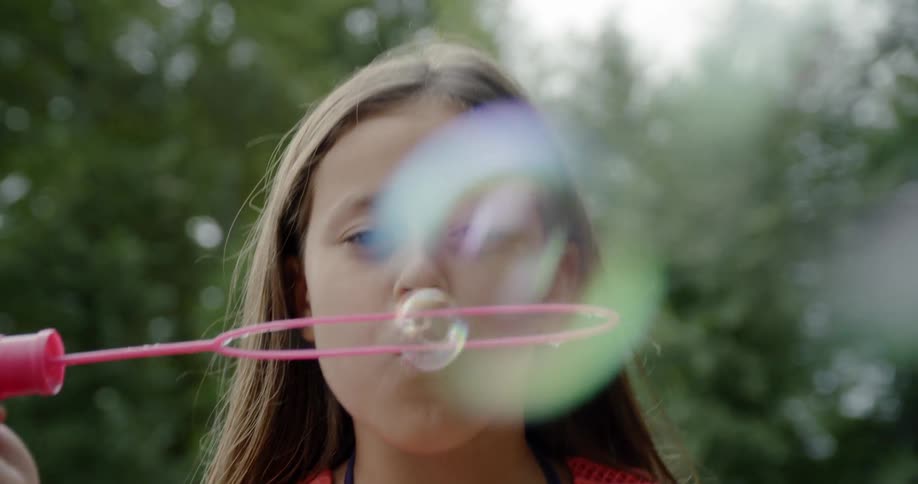 A girl uses a wand to blow bubbles