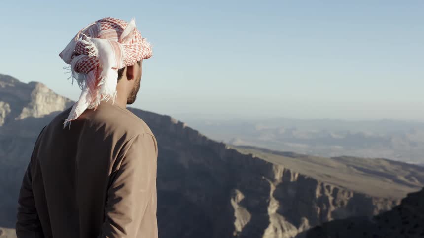 A man looks out over the mountain range from the top