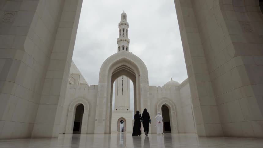 Three people walk towards large tower