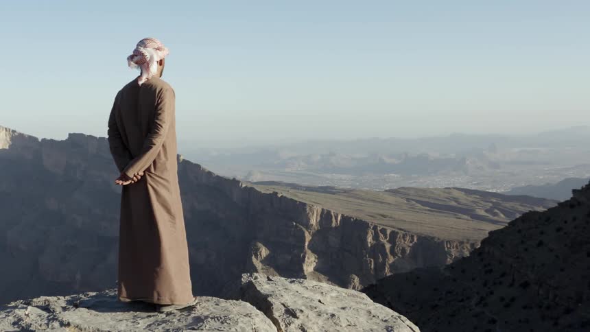 Man stands on rocky mountain looking out at horizon