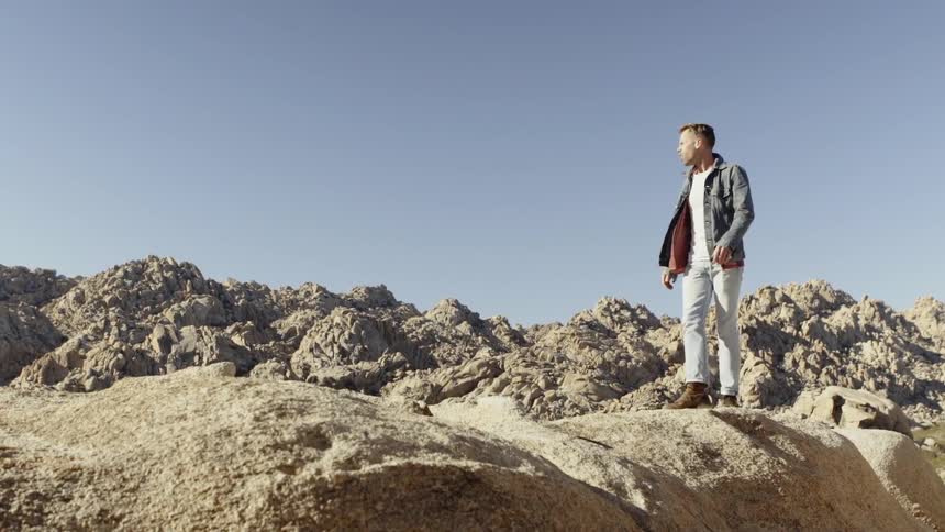 Man walking over a rocky hill on the desert