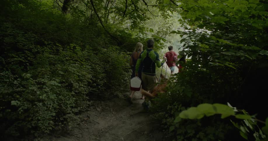 A family and dog walk down the trail towards the lake