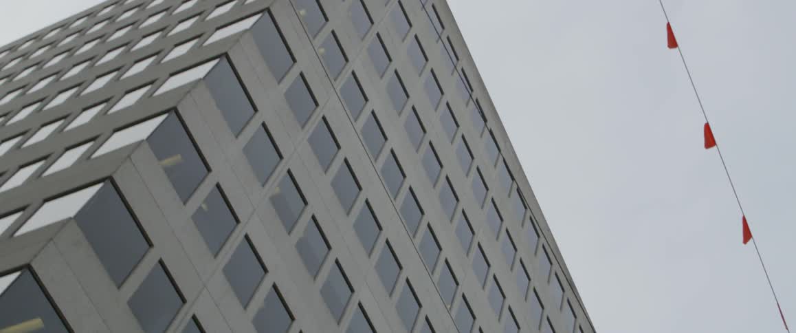 The tall building has flags on a string hanging on the side
