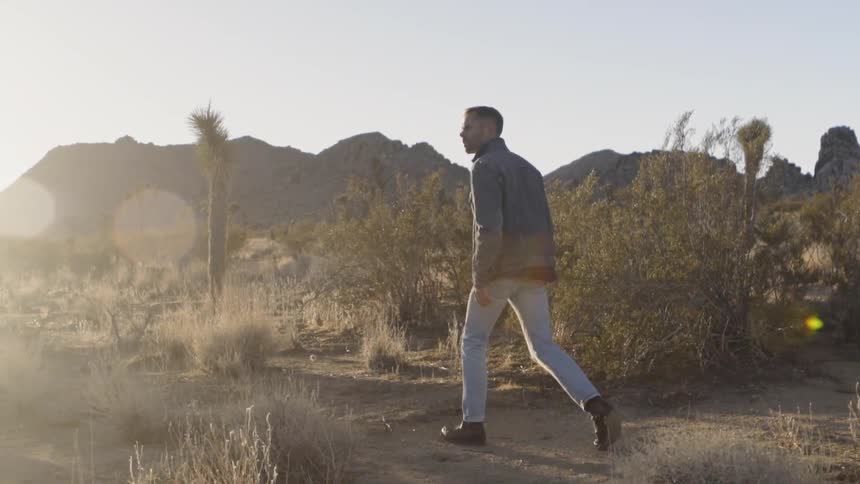 A man walking on a desert at sunset