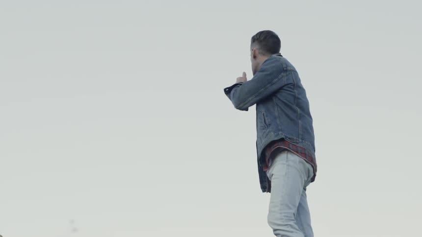Man in jean jacket looks at sky