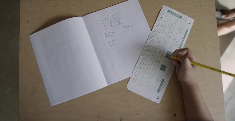 A hand bubbles in answers on a scantron