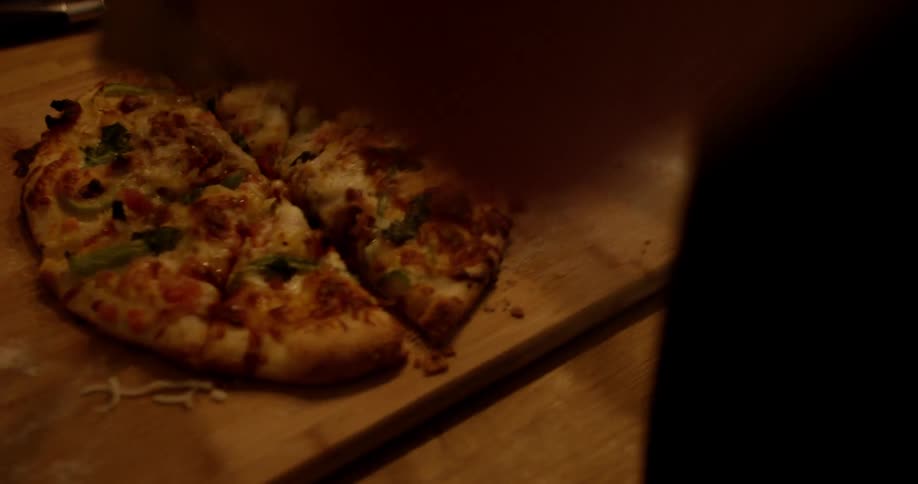 Person cutting a pizza with a large pizza cutter