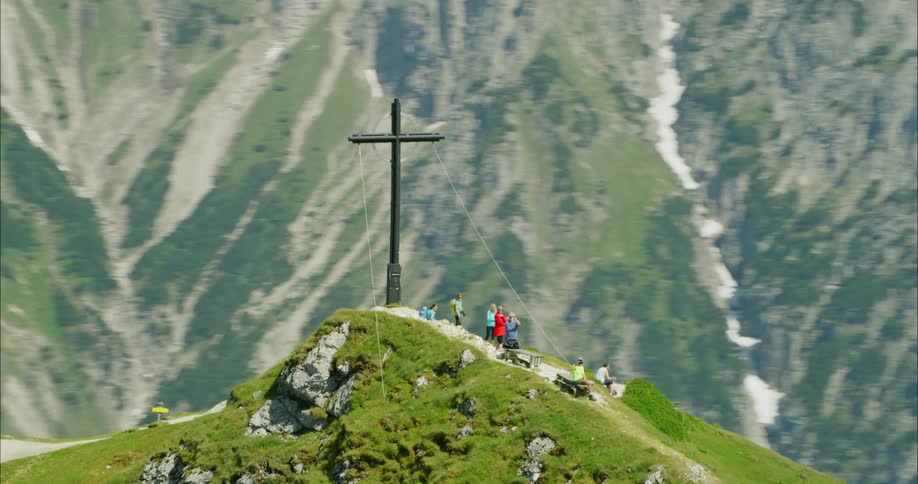 Very large cross on top of a mountain peak with people surrounding it