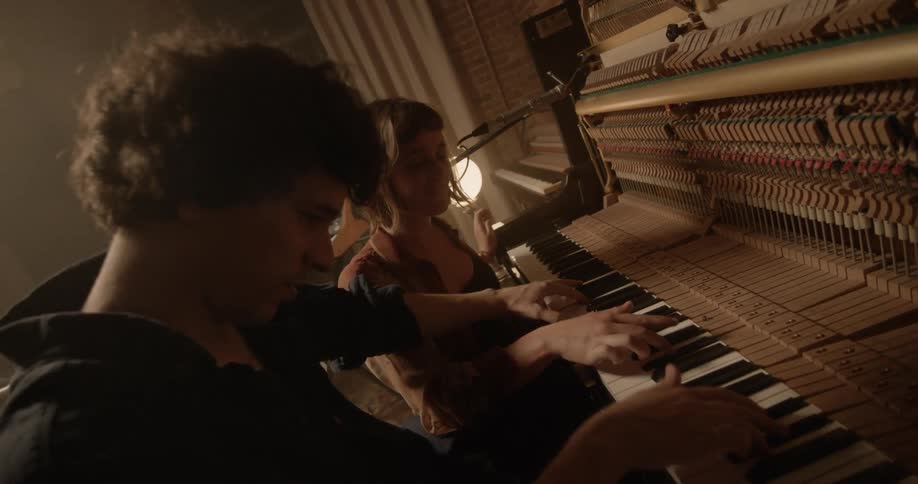 A man and woman are playing piano together