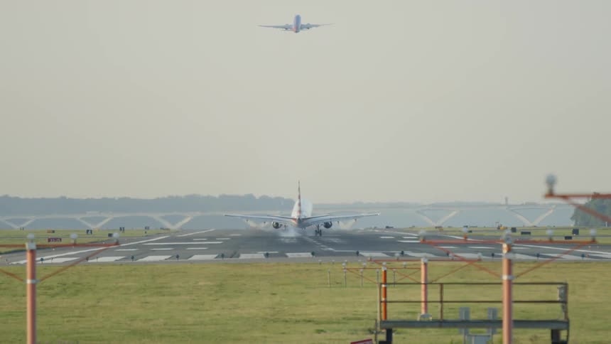 A jet plane lands on a runway while another is taking off