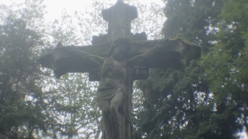 A stone crucifix stands in a cemetery