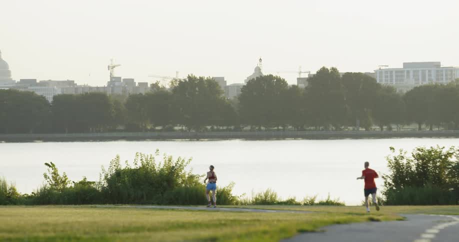People jogging and biking on a park path in an urban area