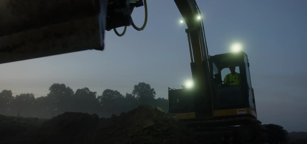 An excavator moves to scoop dirt