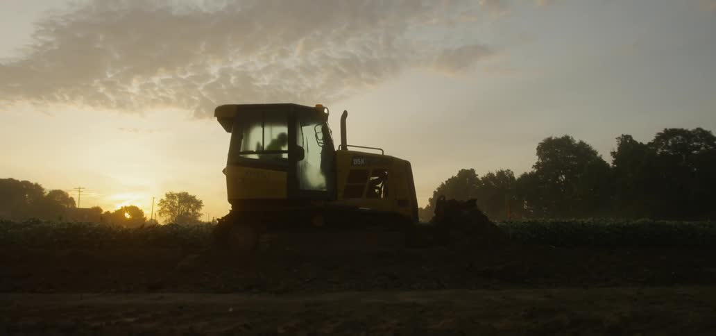 A bulldozer is pushing dirt at sunset