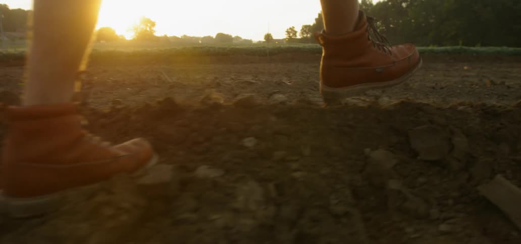 A person in work boots walks across freshly dug earth