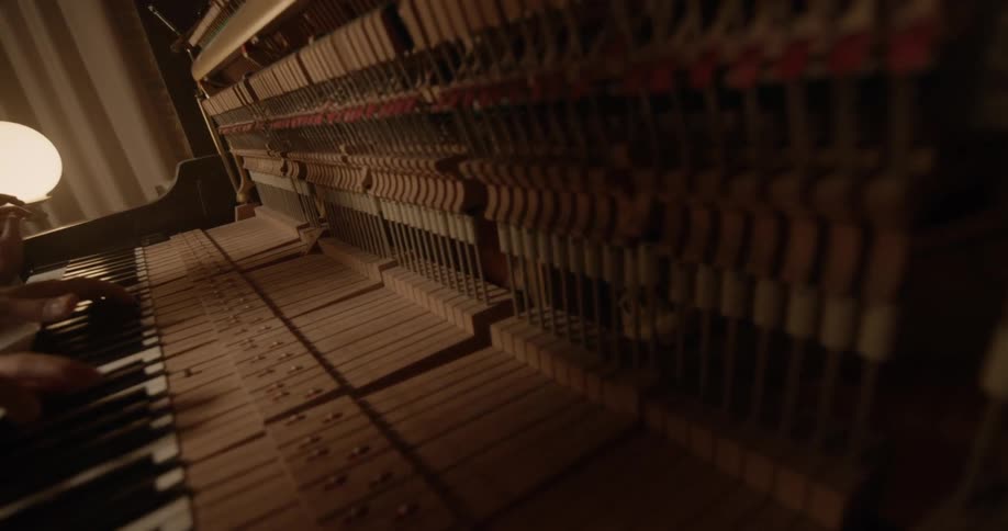 Man and woman play piano together in room at night