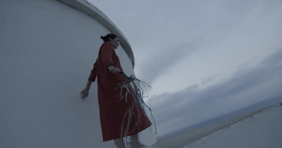 Woman walks near building holding branch