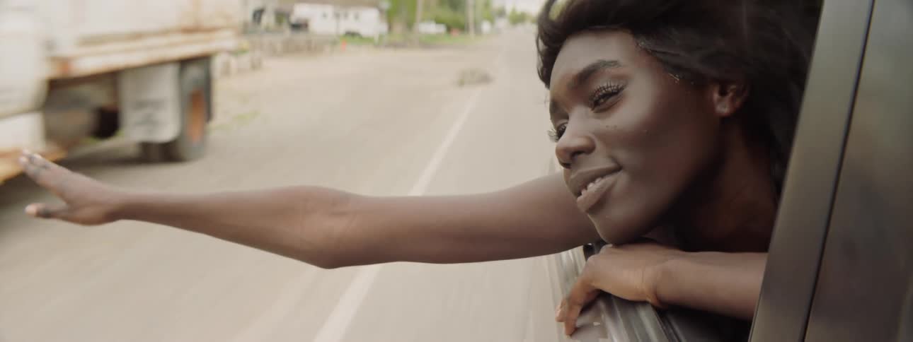 Woman hanging out the window of a car while it's driving