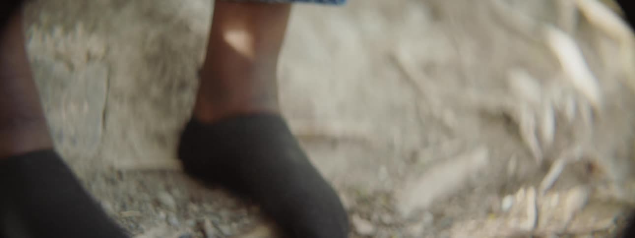 A person takes off their shoes and socks as they sit on the sand