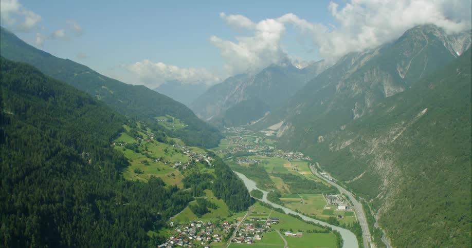 A huge valley sits between two mountains with buildings and a road