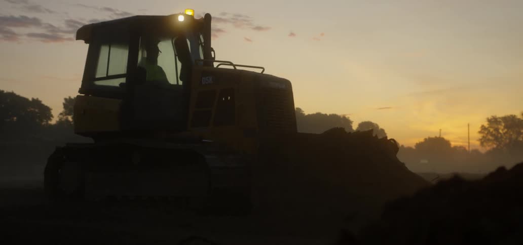 A bulldozer is working at dawn