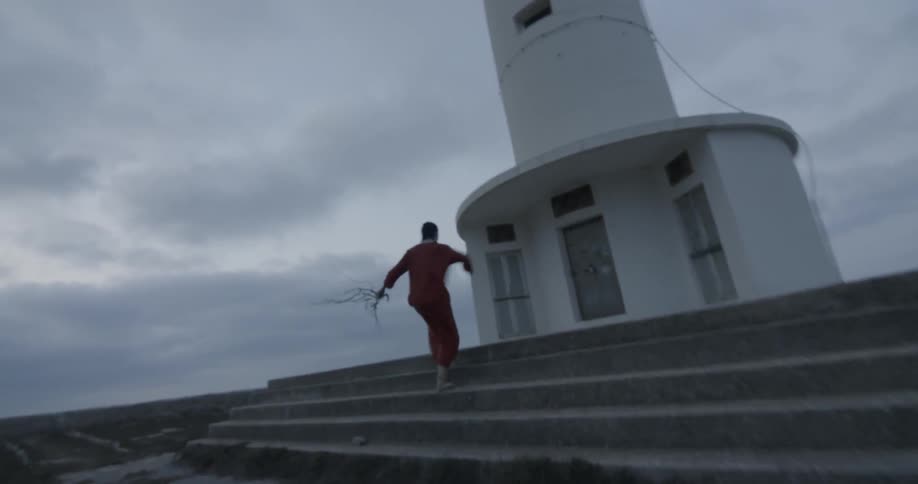 A woman runs up steps leading to a lighthouse