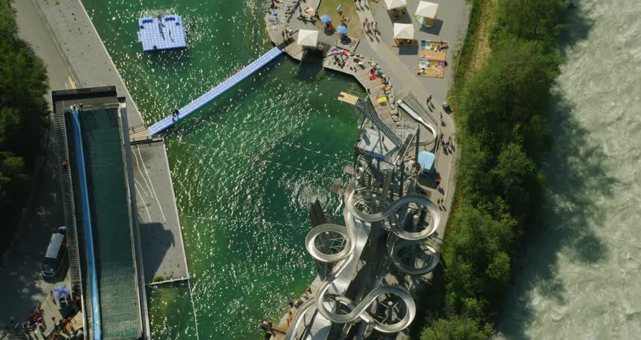A person splashes into the pool from a large slide at the water park on a sunny day