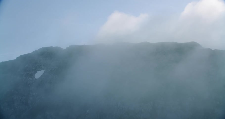 The clouds touch the top of this tall mountain