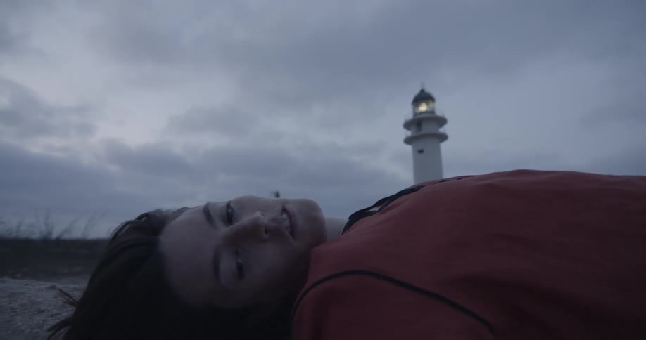 Woman rolls her head from side to side on a beach before a storm