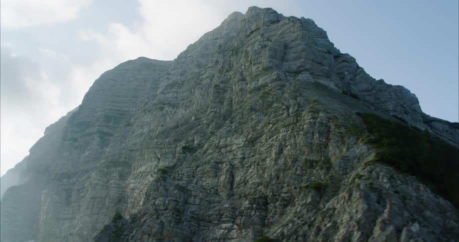 Large rocky mountain near clouds
