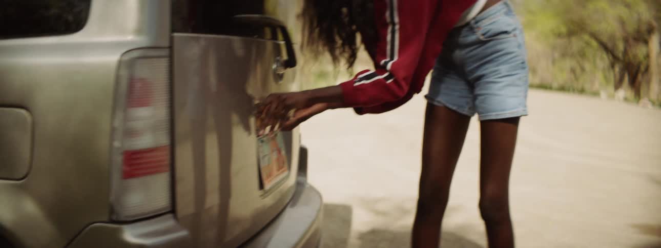 A woman tried to fix the light over the license plate on the back of a vehicle