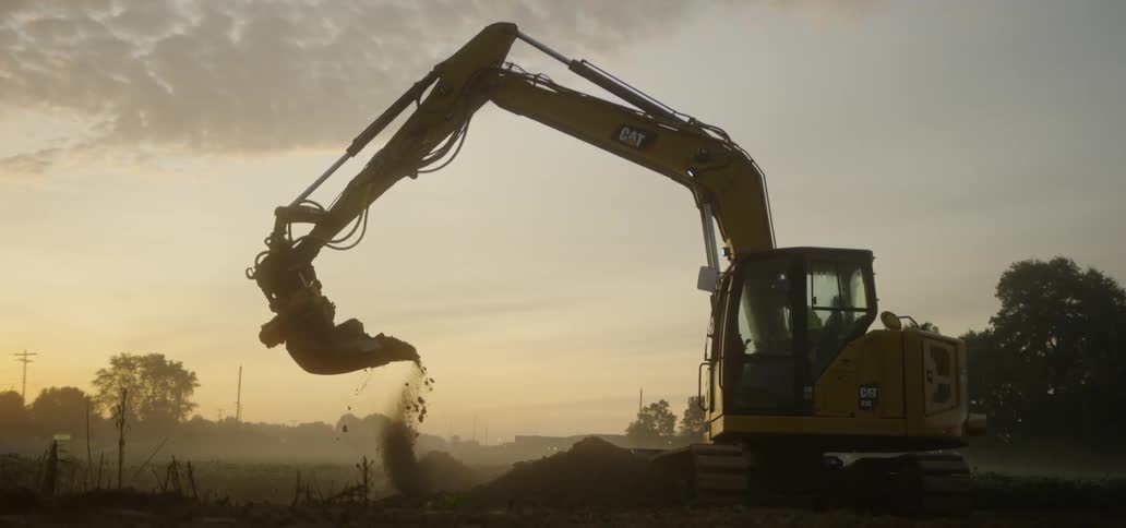A cat digger unloads dirt