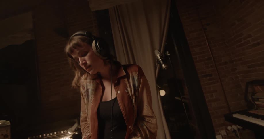 A woman is playing keyboard while wearing headphones