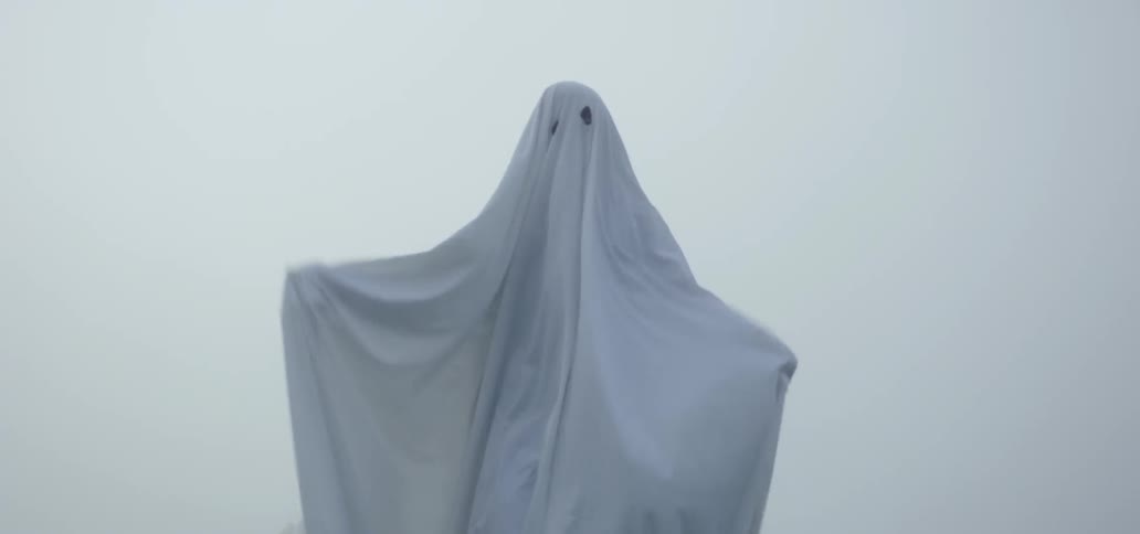 Person in white sheet walks towards camera