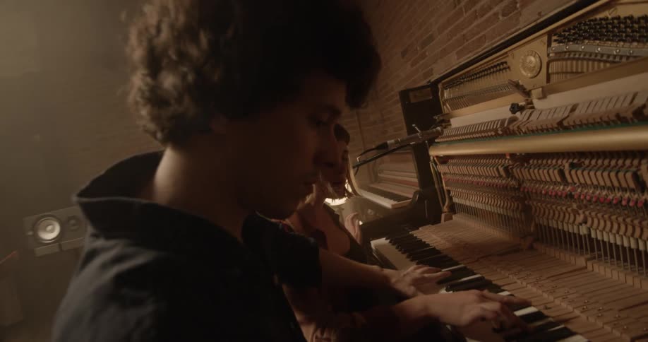 Man plays a keyboard as another man watches