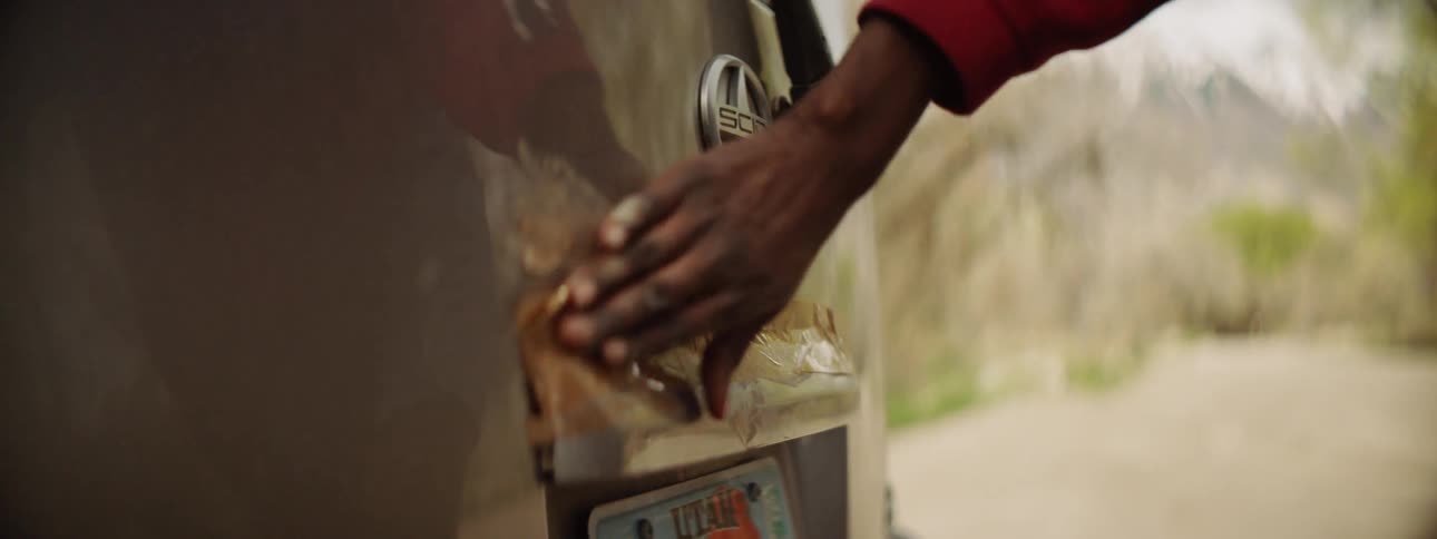 A woman uses tape to fix a backlight to the boot of her car