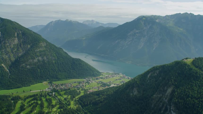 Sun shines down on mountain village near a river on a hazy afternoon