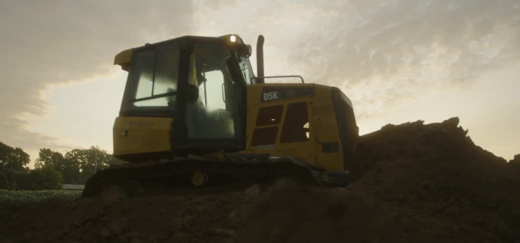 A bulldozer pushes dirt at sunset