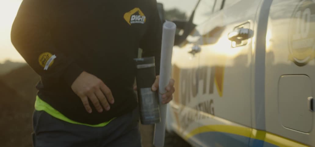 Man closing truck door on construction site with blueprints in hand