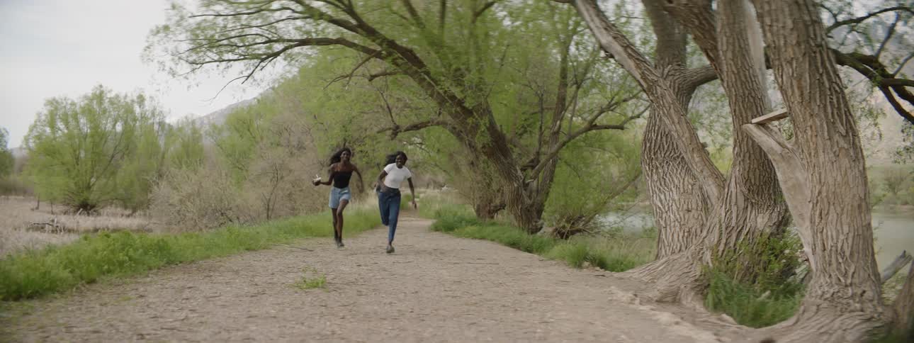 A pair of young women filming themselves while running along a trail
