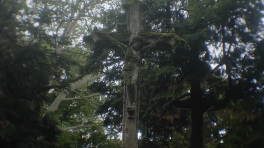 A statue of the christ on his cross in a forest