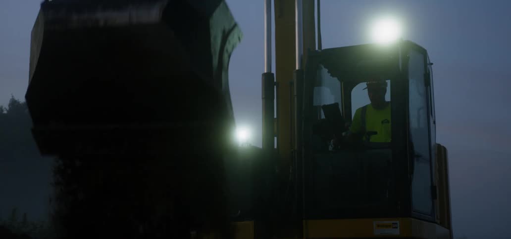 A person is operating a crane and moving dirt