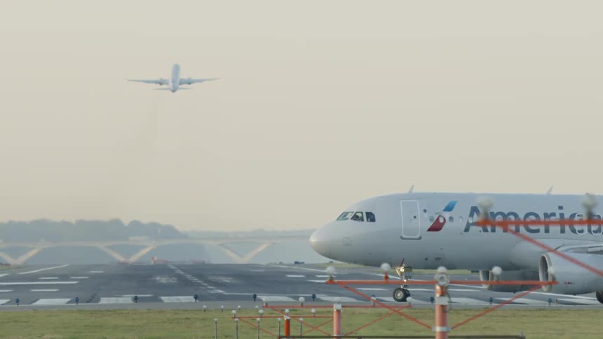 A very large plane taking off from a runway while another drives behind