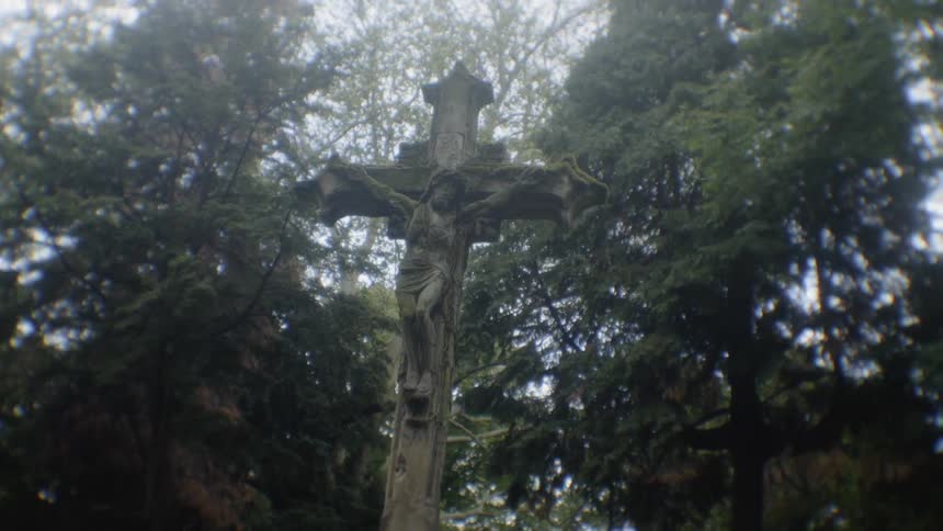 A statue of a cross is outside during day time