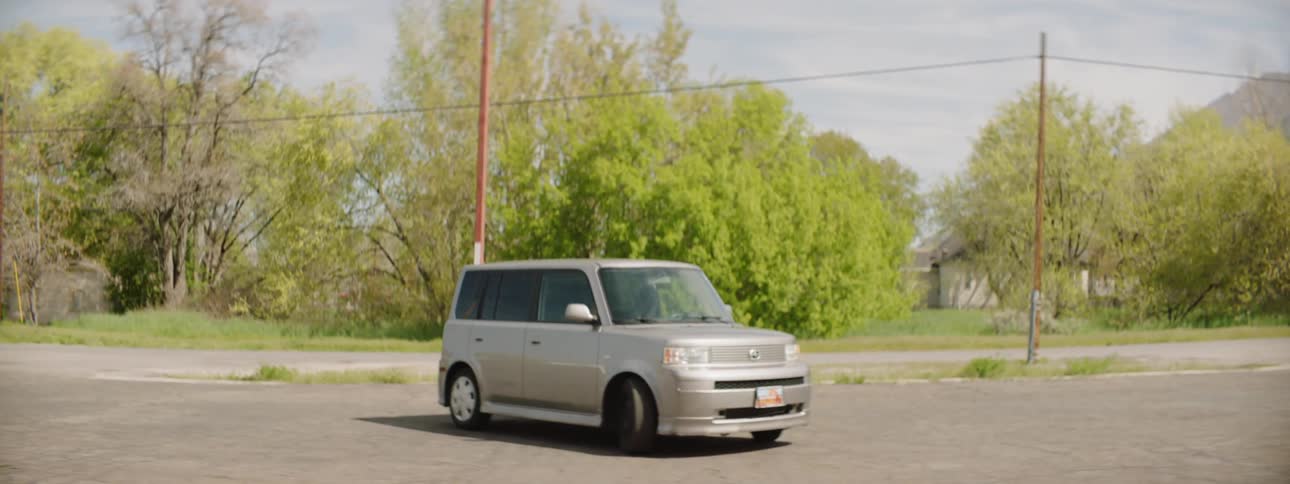 A person backs out of a parking spot and drives off on a sunny day
